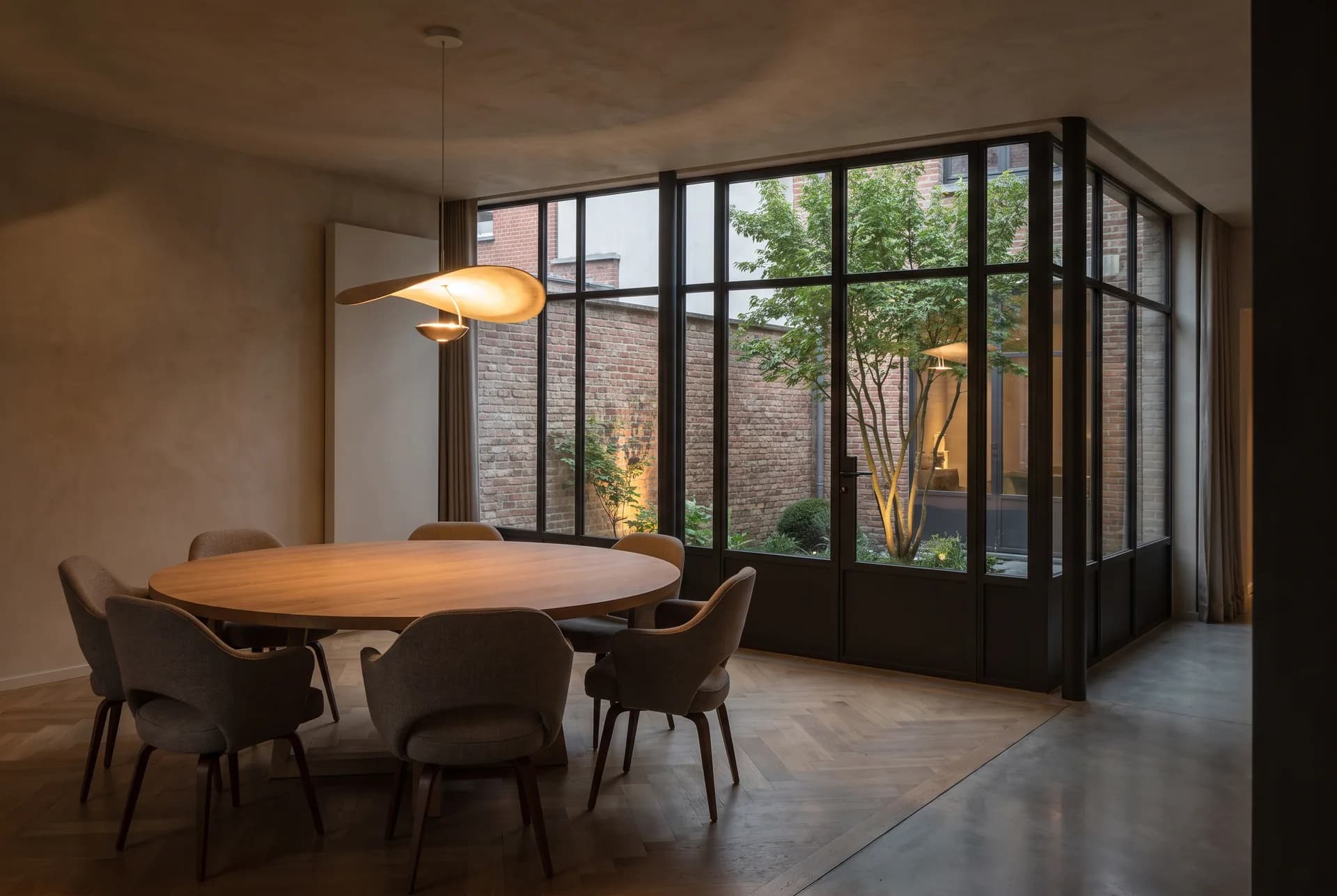 Salle à manger de la Maison M dans l'angle vitré de l'extension, au crépuscule